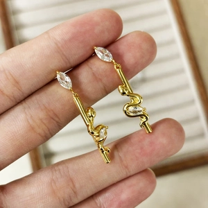 Detailed macro view of 18K gold plated snake drop earrings with marquise zircon stones