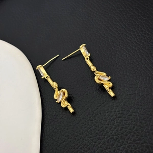 Close-up of golden snake tassel earrings with sparkling zircon inlay on 18K gold plating