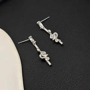 Detail of silver snake drop earrings with sparkling cubic zirconia on a textured background