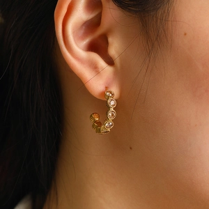 Détail de créoles plaquées or 18 carats avec zircons champagne étincelants et texture ondulée