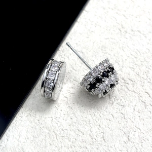 Dettaglio macro di orecchini a semicerchio in argento con pavé di zirconi bianchi e neri