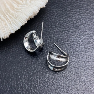 Minimalist silver twisted double hoop earrings on black leather with coral decoration