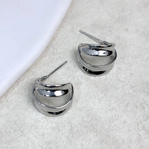Macro detail of silver double C hollow earrings with a high-polish metallic finish