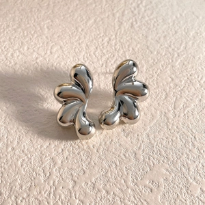 Primer plano de pendientes de botón plateados con ondas irregulares y acabado pulido