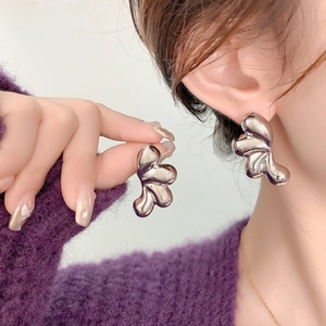 Vista detallada de pendientes de gota plateados con acabado metálico en una modelo