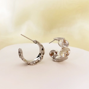 Close-up of silver-tone C-shape geometric earrings with textured disc splicing design