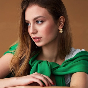 Close-up of stacked gold geometric C-shaped earrings worn by a model in a luxury style