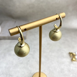 Vintage brushed brass ball drop earrings hanging on a golden T-stand display