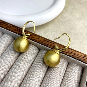 Minimalist vintage brass ball hook earrings with brushed gold finish on jewelry box