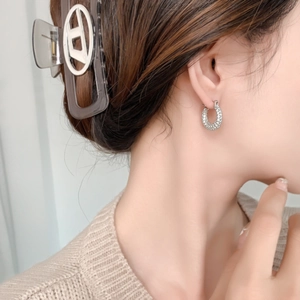 Close-up of elegant silver hoop earrings with pavé micro-set cubic zirconia on female model