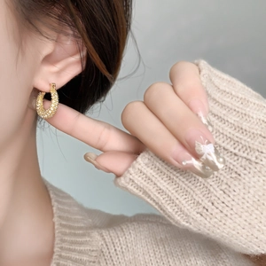 Elegant gold U-shaped hoop earrings with micro-set zircons on a model side profile