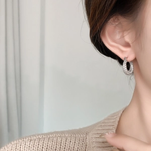 Close-up of silver hoop earrings with pave-set zircons worn by a model in soft lighting