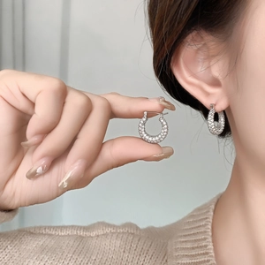 Close-up of silver-tone horseshoe hoop earrings with shimmering pavé zircon stones