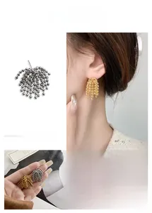 Détails de boucles d'oreilles à pompons perlés en or et argent sur un mannequin