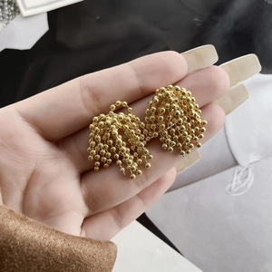 Vue détaillée de boucles d'oreilles pompons dorés avec texture florale en grappes