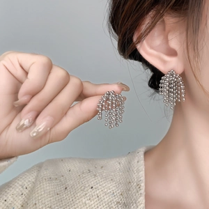 Gros plan de boucles d'oreilles à pampilles en perles argentées avec franges géométriques