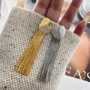Detail view of heart-shaped tassel earrings with long metallic chains and crystal accents