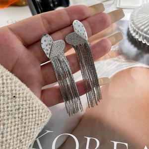 Macro detail of silver tassel earrings with asymmetric heart design and sparkling zircons