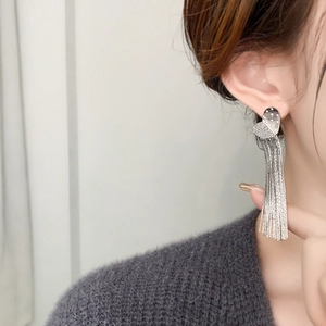 Close-up of elegant silver heart tassel earrings with sparkling rhinestones on a model