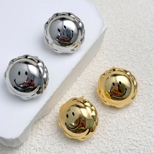 Detailed close-up of gold and silver smiley face button earrings with textured edges