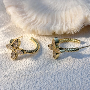 Golden C-shaped twisted rope earrings featuring sparkling zircon-set four-petal flowers