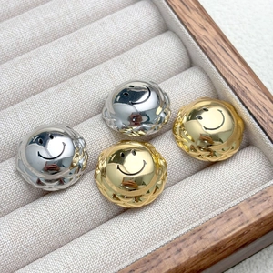 Close-up of gold and silver smiley face earrings with luxury quilted edge details