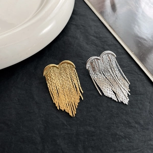 Detailed view of heart-shaped tassel earrings in gold and silver metallic finishes