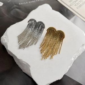 Close-up of heart-shaped earrings with layered metal tassels in gold and silver finish