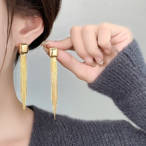 Close-up of elegant gold long chain tassel earrings featuring minimalist cube design