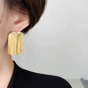 Close-up of long tassel earrings with sparkling zircons and 18K gold-plated chains