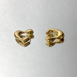 Boucles d'oreilles cœur plaqué or 18 carats posées sur une surface miroir polie