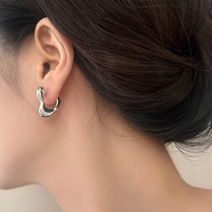 Boucles d'oreilles cœur argentées minimalistes au design métal liquide sur un mannequin