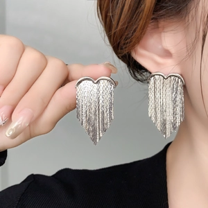 Macro view of silver heart earrings with dangling fine metal chain tassels and high-shine finish