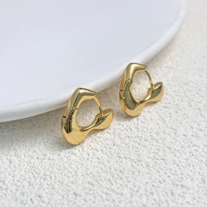Gros plan de boucles d'oreilles cœur plaquées or 18K avec texture fluide sur céramique