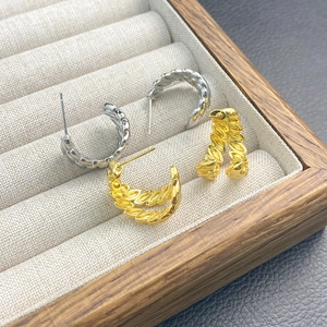 Detail view of gold and silver twisted hoop earrings in a velvet display box