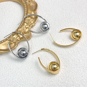 Detailansicht geometrischer Spiralohrringe mit polierten Metallperlen in Gold und Silber