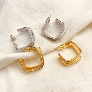 Minimalist square geometric earrings in 18k gold and silver finish on linen background