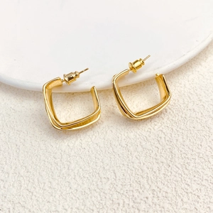 Macro shot of minimalist twisted square hoop earrings in polished 18k gold plating