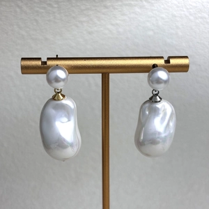 Detailed close-up of Baroque pearl earrings on a gold stand showing natural luster