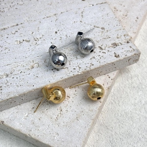 Minimalist gold and silver hollow spherical earrings with textured vertical lines on stone