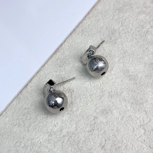 Detailed view of silver minimalist spherical stud earrings with vertical texture and 18K plating