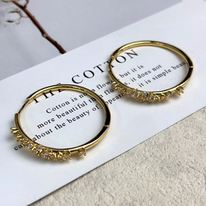 Dettaglio di orecchini a cerchio placcati oro 18K con pavé di zirconi scintillanti