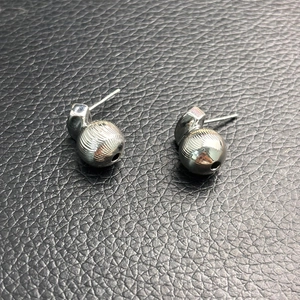 Detailed close-up of silver-tone hollow sphere earrings with vertical striped textures