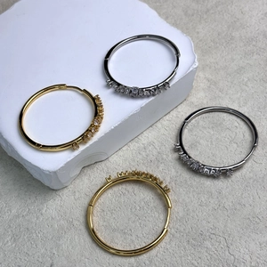 Dettaglio di orecchini a cerchio in oro 18K e argento con zirconi su marmo