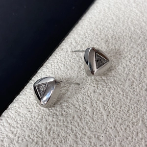 Macro detail of triangle stud earrings with hollow mesh texture and S925 silver hallmark