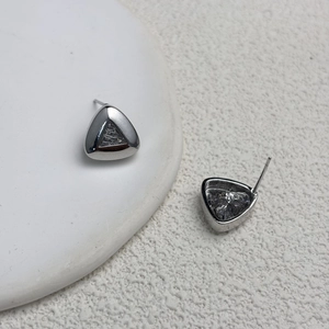Macro shot of silver triangle stud earrings with hollow geometric frame and zircon inlay