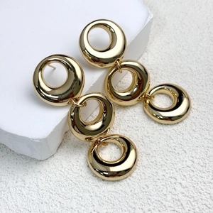 Detailed macro view of triple linked gold circle chain earrings on a white stone pedestal