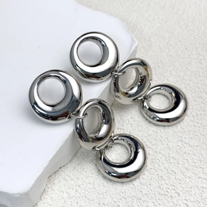 Macro detail of high-polish silver interlocking triple ring chain earrings on stone