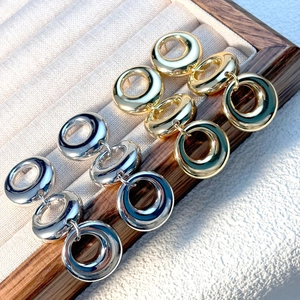 Detailed view of gold and silver triple geometric linked ring earrings in a jewelry box