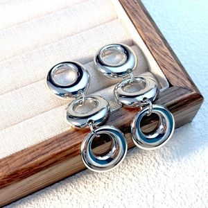 Polished silver triple interlocking hoop earrings displayed in a luxury wooden jewelry box